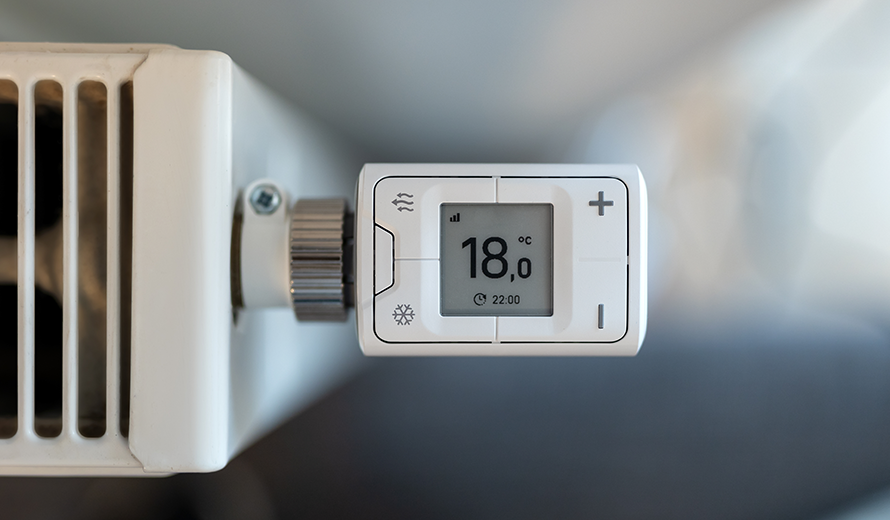 Ein digitales Thermostat an einer Heizung zeigt 18 Grad Celsius an.