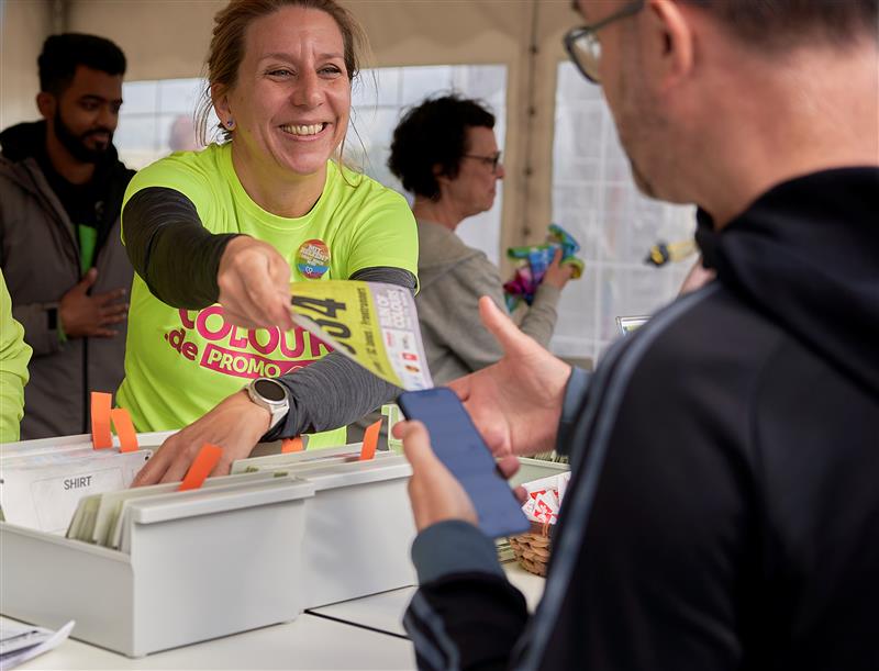 Elfi Pfahlbusch teilt Startnummern beim Kölner Run of Colours aus