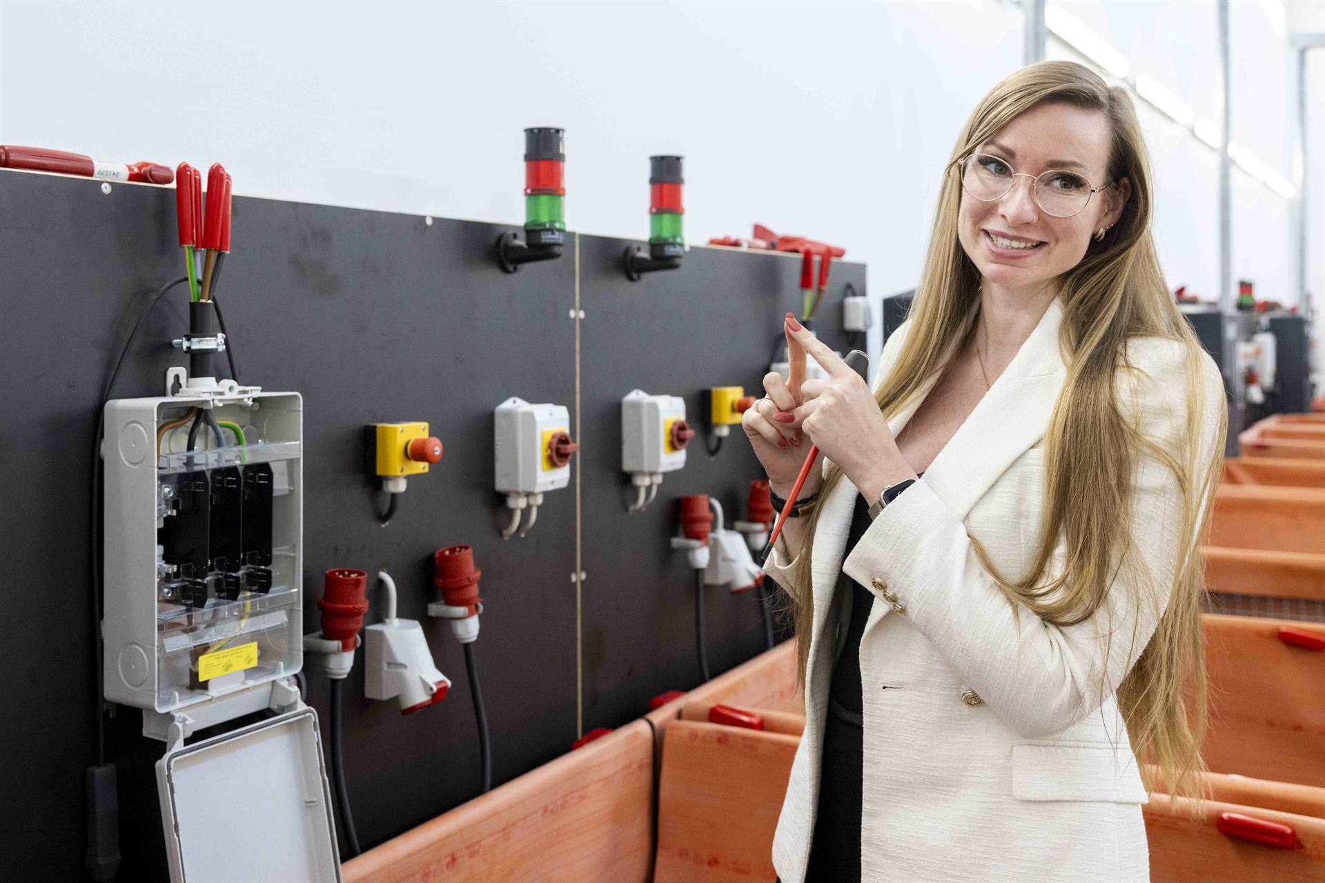 Silke Brinkschröder ist Trainerin für Arbeiten unter Spannung und zeigt auf die Kabel an einem Hausanschlusskasten