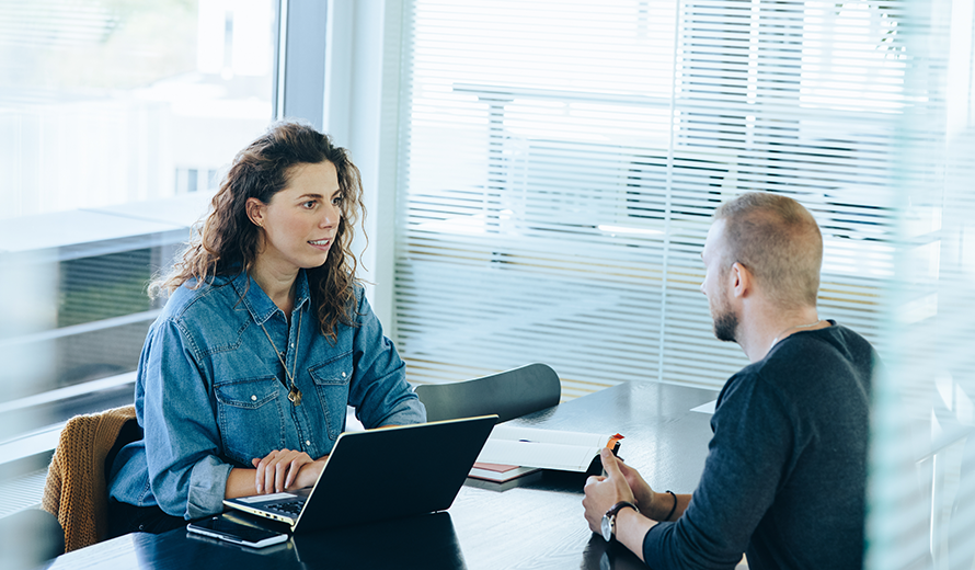 Situation eines Bewerbungsgesprächs zwischen einer dunkelhaarigen Frau und einem jungen Mann. 