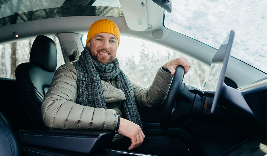 Ein Mann mit gelber Mütze sitzt am Steuer eines Elektroautos.