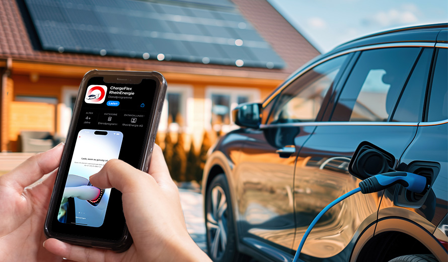 Mensch steht vor Haus mit PV-Anlage und bedient neben seinem E-Auto die ChargeFlex-App auf seinem Handy.